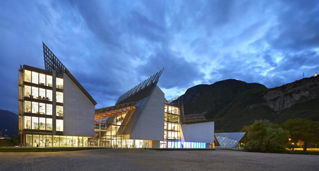 a large building with a mountain in the background at Komodo short stay apartments in Trento