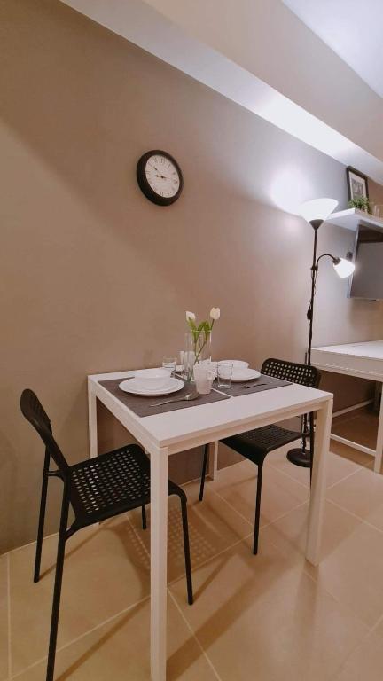 a dining room table with two chairs and a clock on the wall at The Nook at Serin Tagaytay in Tagaytay
