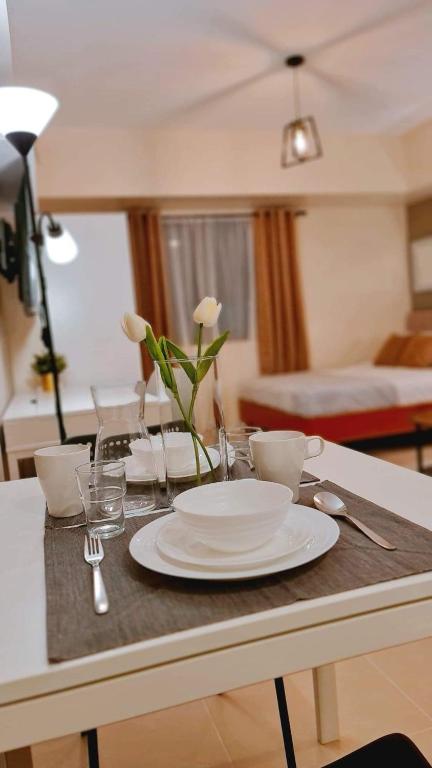 a table with a white plate and glasses and a bed at The Nook at Serin Tagaytay in Tagaytay