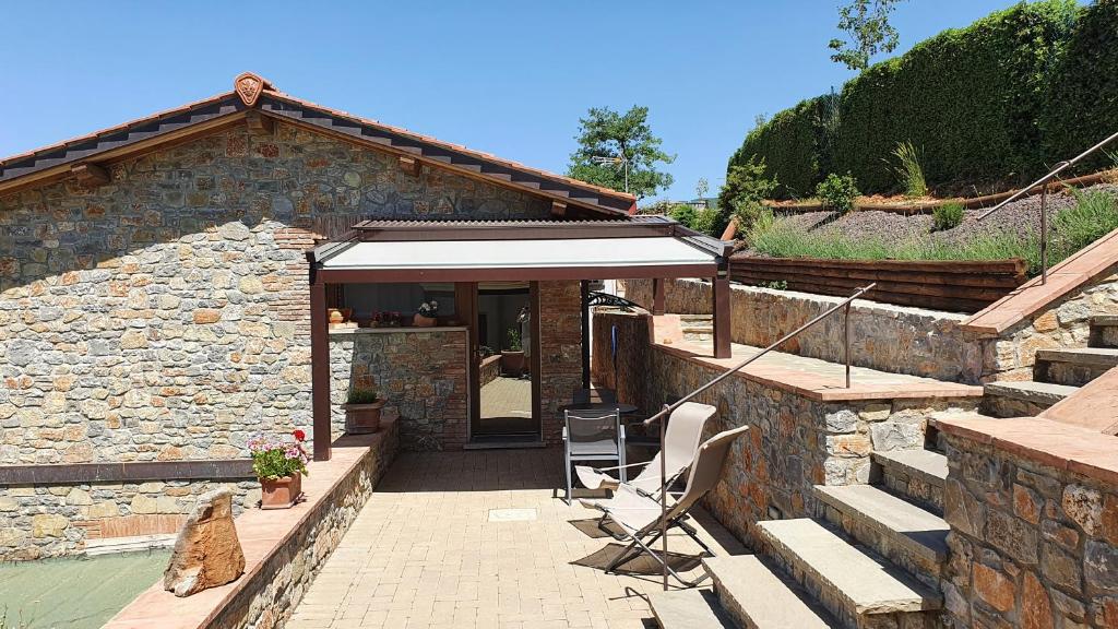 a stone house with an umbrella and two chairs at Casa Ciaccheri 2 in Gaiole in Chianti
