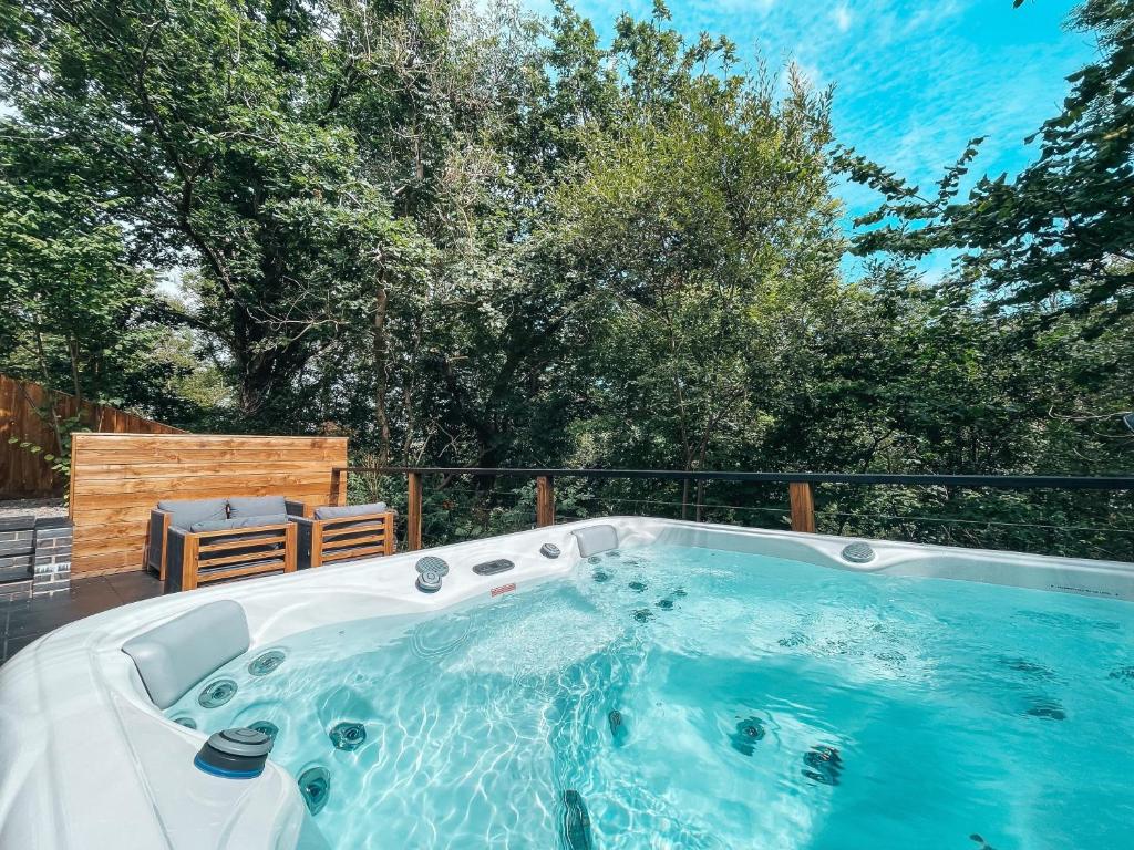 een hot tub op een patio met bomen op de achtergrond bij Falls Cottage by Solace Stays in Merthyr Tydfil