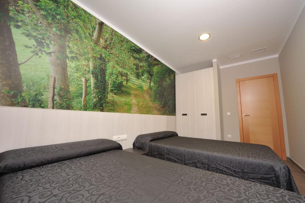 a bedroom with two beds and a painting on the wall at Aparthotel Meseguer in Alcañiz