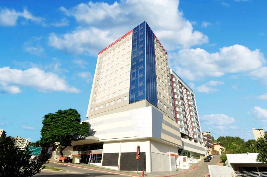 a tall building with blue windows on a street at Easy Hotel Cachoeiro de Itapemirim by Atlantica in Cachoeiro de Itapemirim