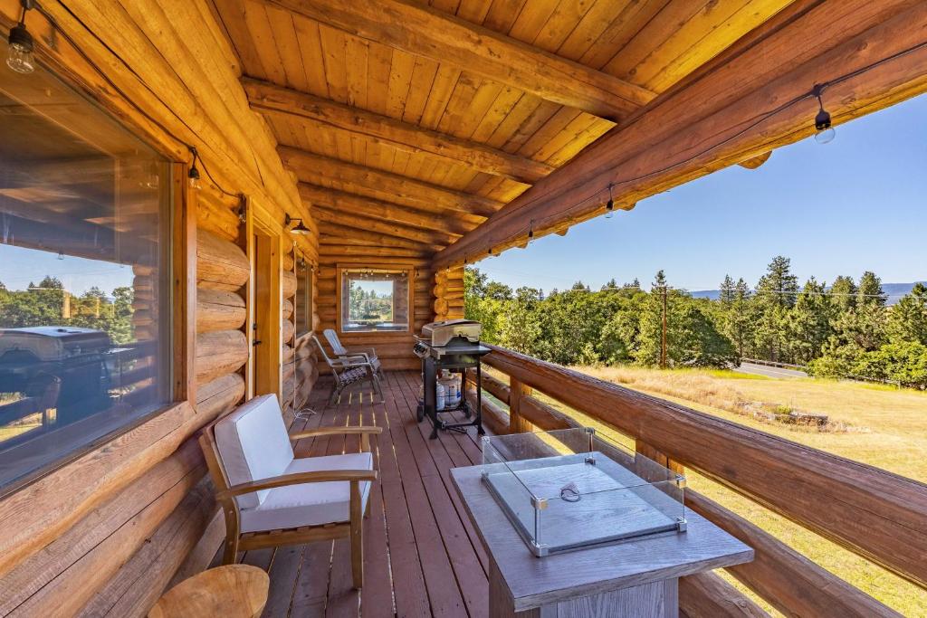 une terrasse couverte d'une cabine avec un grill et des chaises dans l'établissement Rowland Log Cabin home, à Lyle