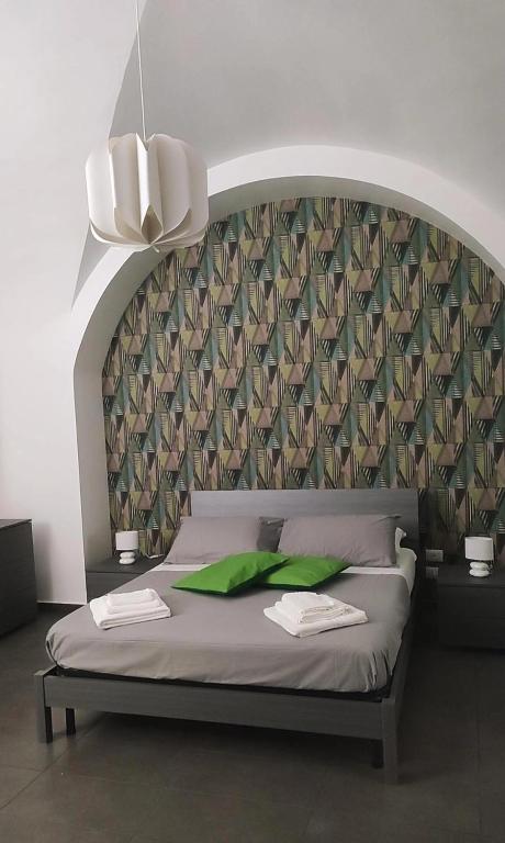 a bedroom with a large bed with green pillows at Fortino vecchio apartment in Catania