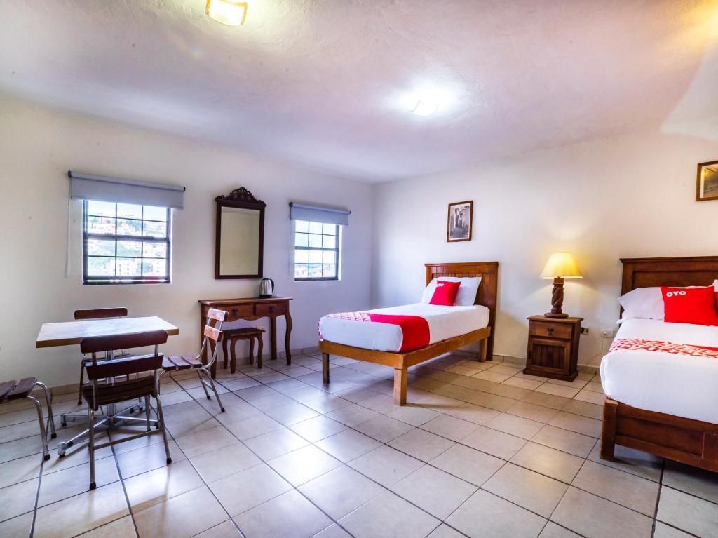 a bedroom with two beds and a desk and a table at Casa Banqueta Alta in Guanajuato