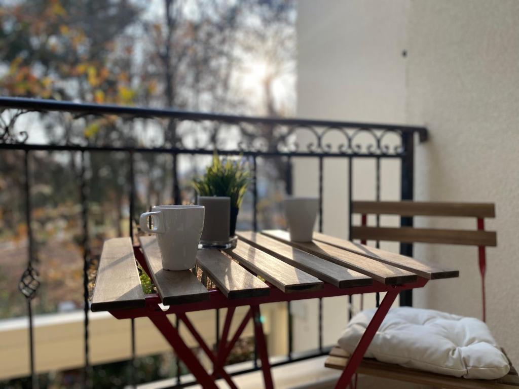a wooden table with two cups on a balcony at Green park Sandanski in Sandanski