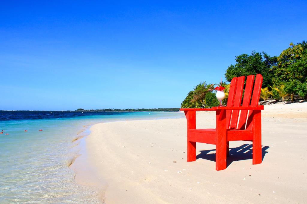 a red chair sitting on a beach near the water at Stevensons at Manase in Manase