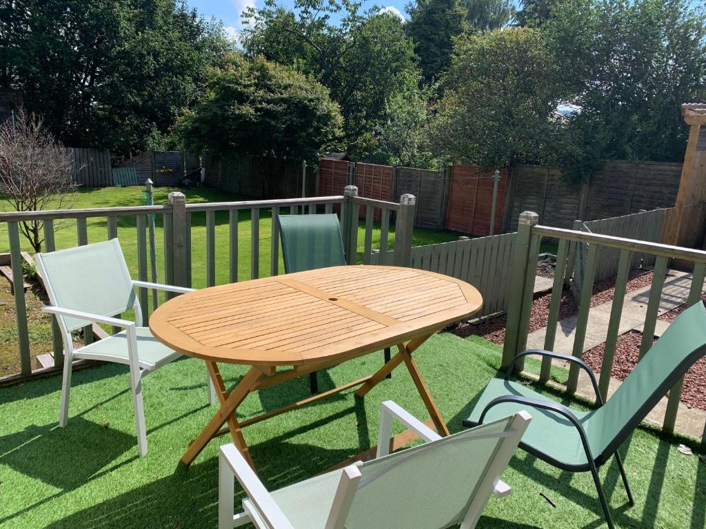 a wooden table and four chairs on a lawn at Nairoo in Balloch