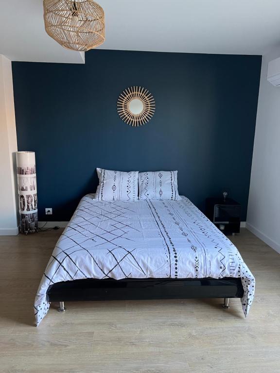 een slaapkamer met een bed met een blauwe muur bij Studio cartel in Le Bosc