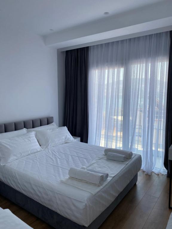 a bedroom with a bed with white sheets and a window at SEA & LAKE VIEW VILLA in (( Kalive Gjoka ))