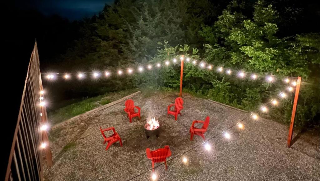 um quintal com cadeiras vermelhas e uma lareira e luzes em Enchanted Forest Retreat em Dandridge