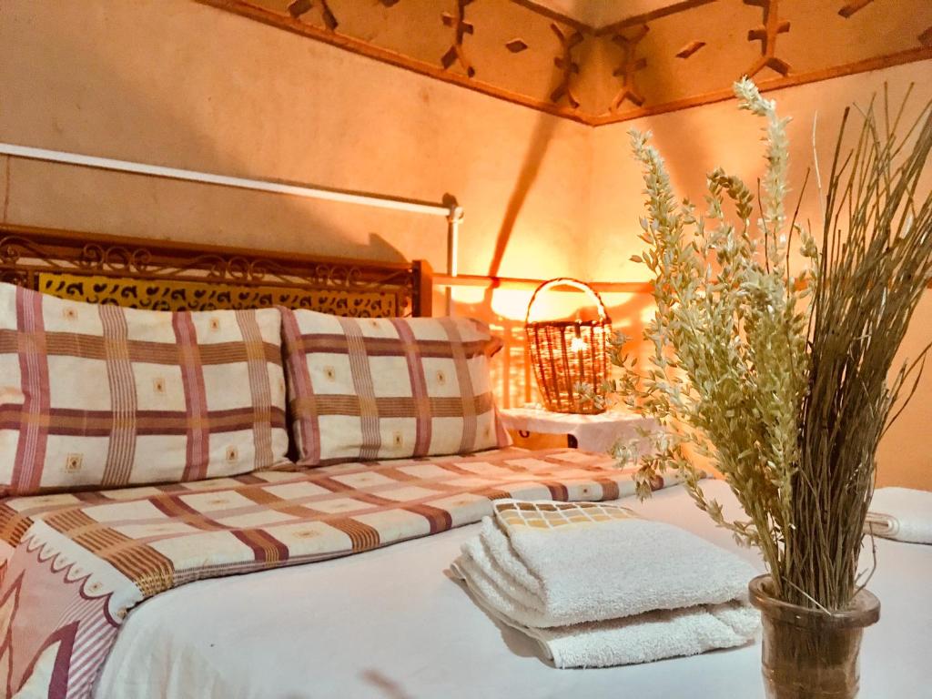 ein Schlafzimmer mit einem Bett und einer Vase mit Handtüchern in der Unterkunft Hôtel panoramique de la vallée in Aït Idaïr