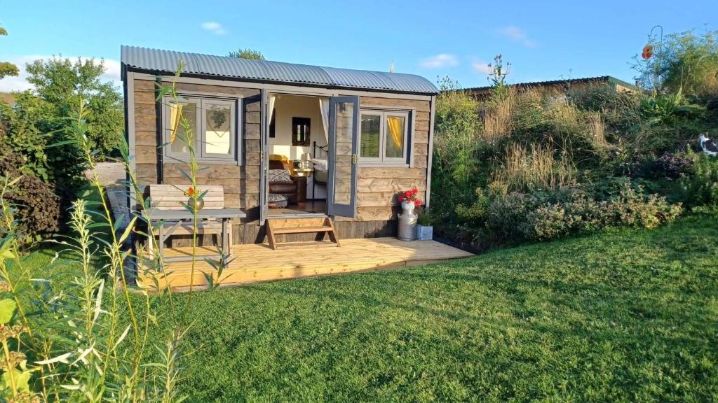 ein winziges Haus mit einer Terrasse im Garten in der Unterkunft Rhodes To Serenity - Mermaid Shepherds Hut in Stoke on Trent