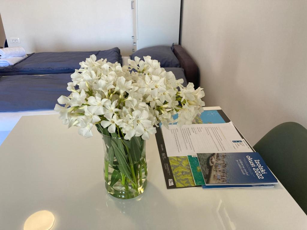 un vase de fleurs blanches sur une table avec un livre dans l'établissement Bellevue 1, à Izola