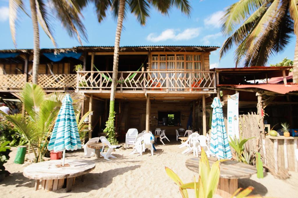 a resort with chairs and tables on the beach at Puerto Manglar Hostel in Guachaca