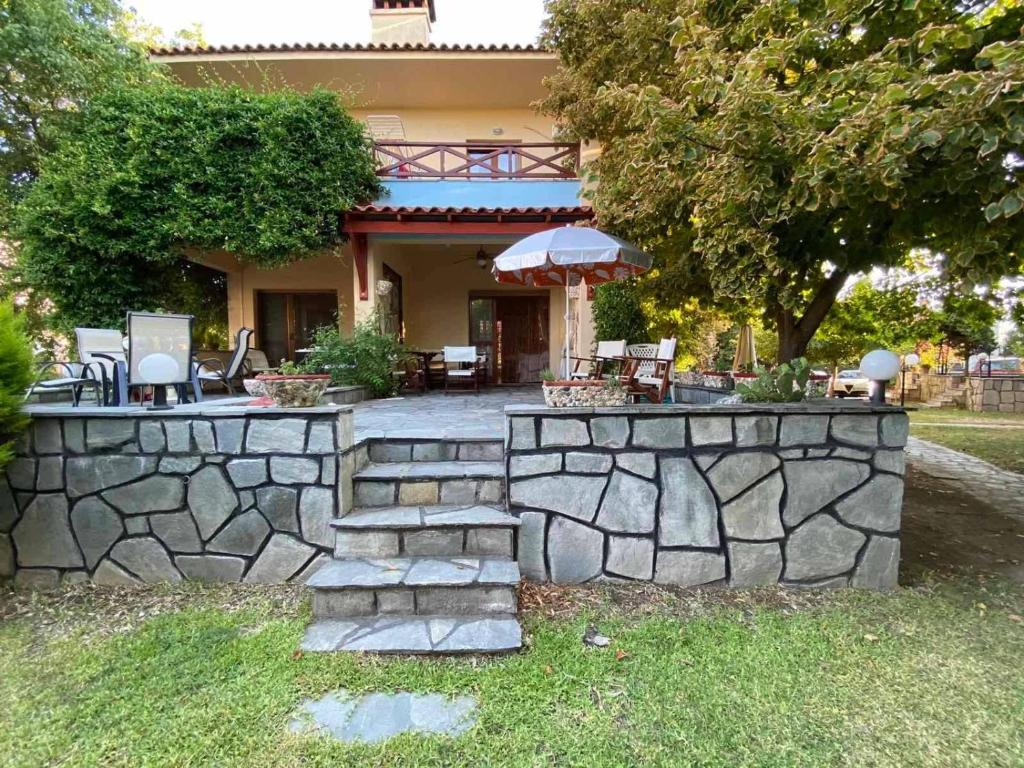 un muro de contención de piedra frente a una casa en Georgia's house, en Nikiti
