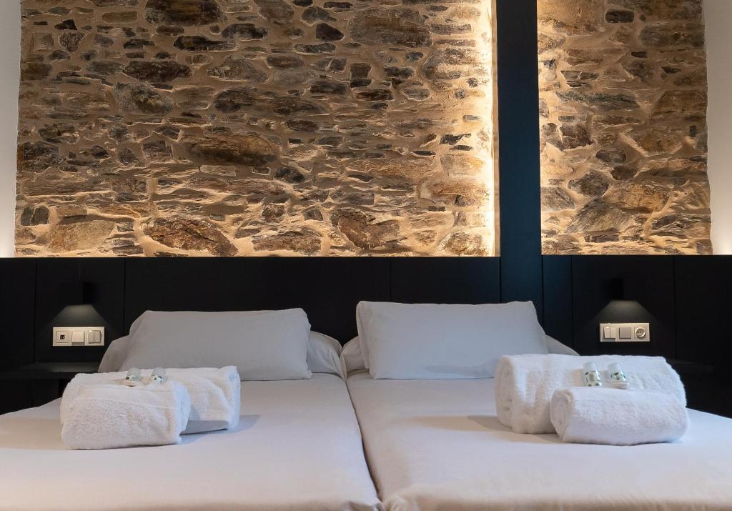 1 cama con toallas y pared de piedra en Ultreia Seven Rooms by Adeloló, en Santiago de Compostela