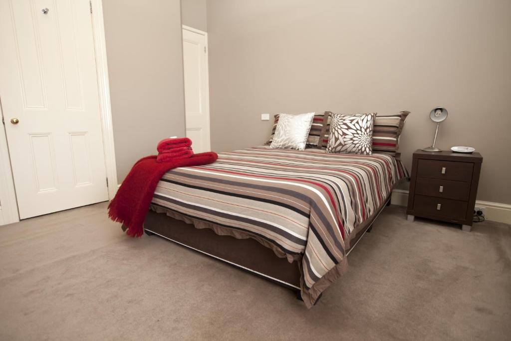 a bedroom with a bed with a red blanket on it at Allawah Bendigo in Bendigo