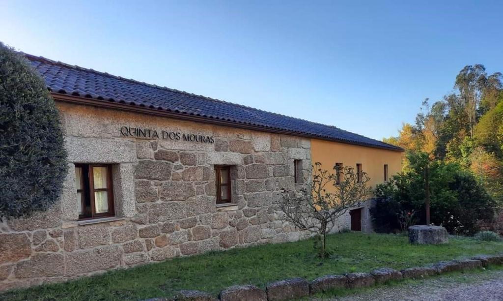 ein Steingebäude mit einem Schild an der Seite in der Unterkunft Quinta dos Mouras B&B in Rebordões