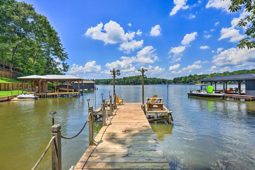 a dock on a lake with a house on it at Lakefront Eatonton Getaway with Dock and Grill! in Resseaus Crossroads