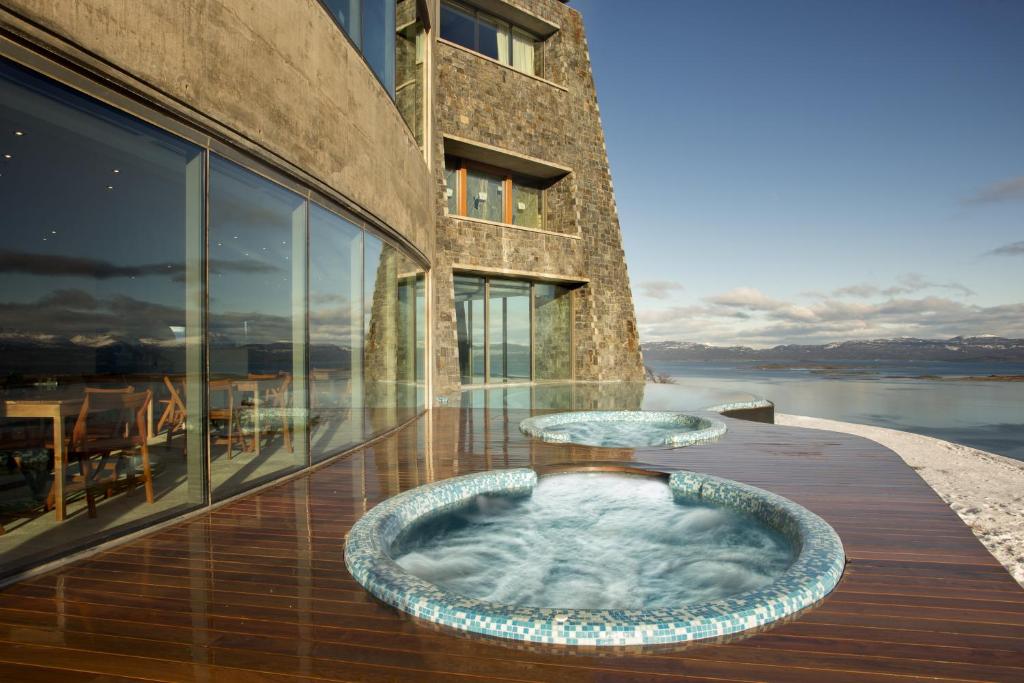 bañera de hidromasaje en una terraza frente a un edificio en Arakur Ushuaia Resort & Spa en Ushuaia