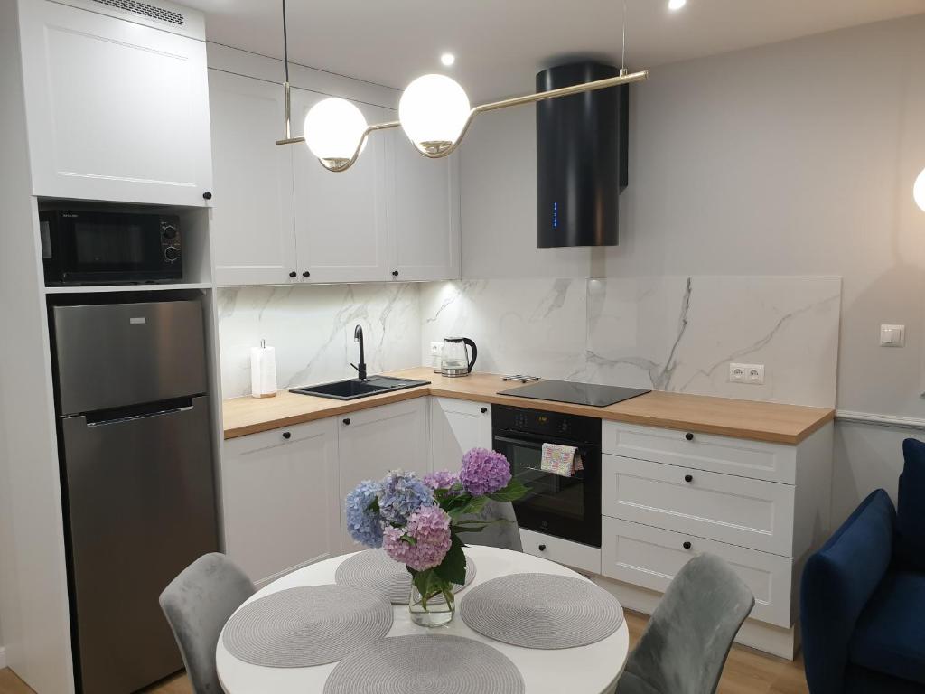 a kitchen with a table with a vase of flowers on it at Apartament Margot - Centrum in Tarnów