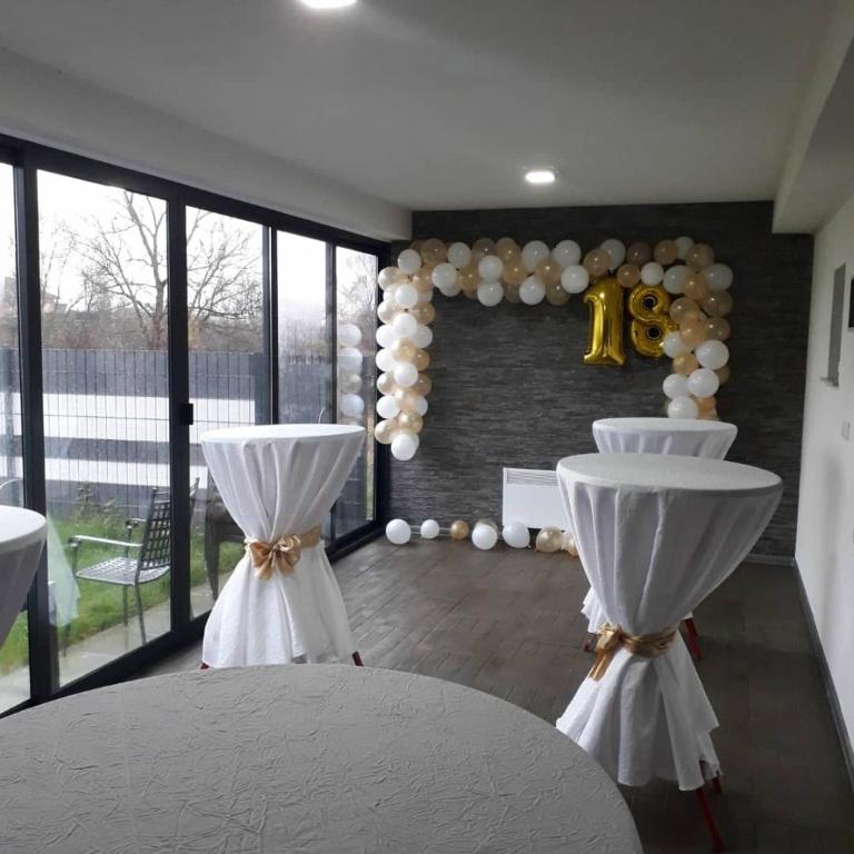 a room with two white tables and a balloon wall at Vikendica Sana in Gomjenica