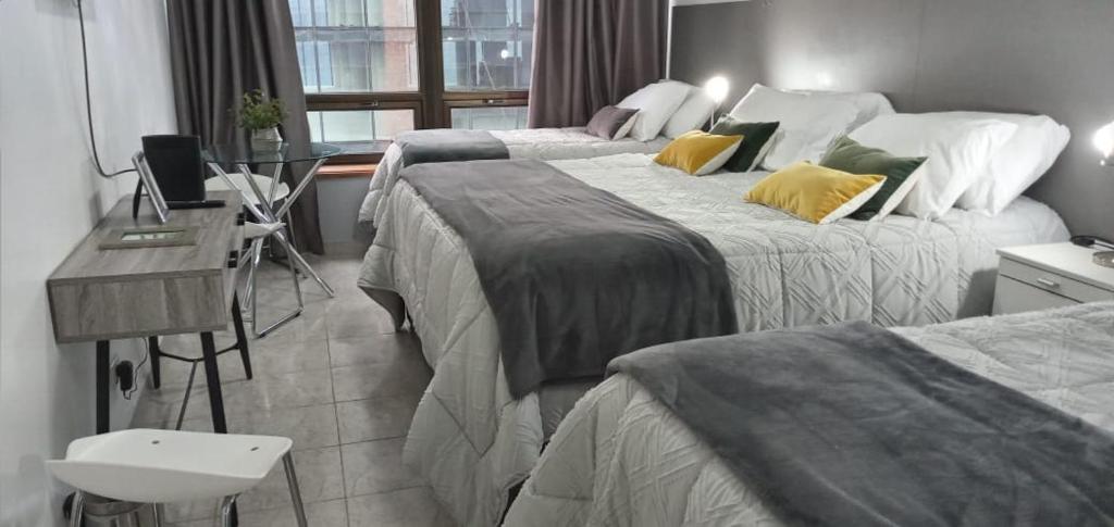 a hotel room with two beds and a desk at CORAZOn BUENOs AIREs PLATINo in Buenos Aires