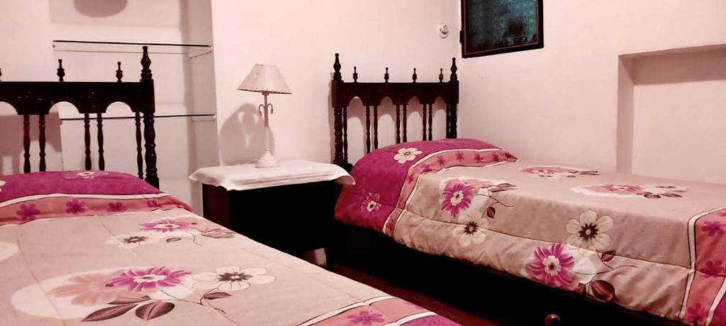 two beds in a room with pink sheets and flowers at Casa de Oda in Salta