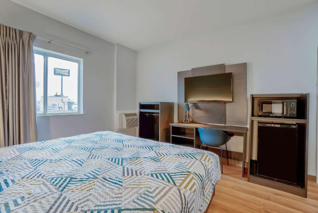a bedroom with a bed and a desk with a microwave at Motel 6-Denison, TX in Denison