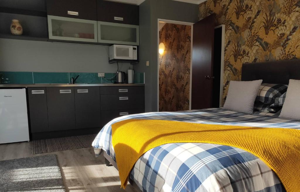 1 dormitorio con 1 cama con manta amarilla en Heart of Kerikeri - The Studio, en Kerikeri