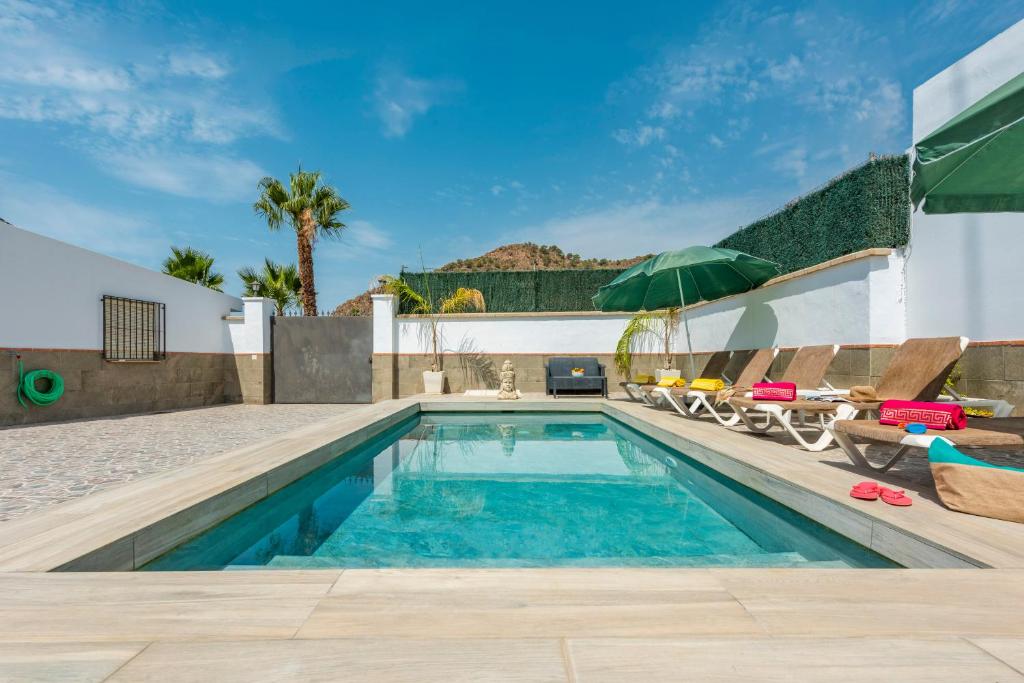a swimming pool with chairs and an umbrella at Villa La marina in Nerja