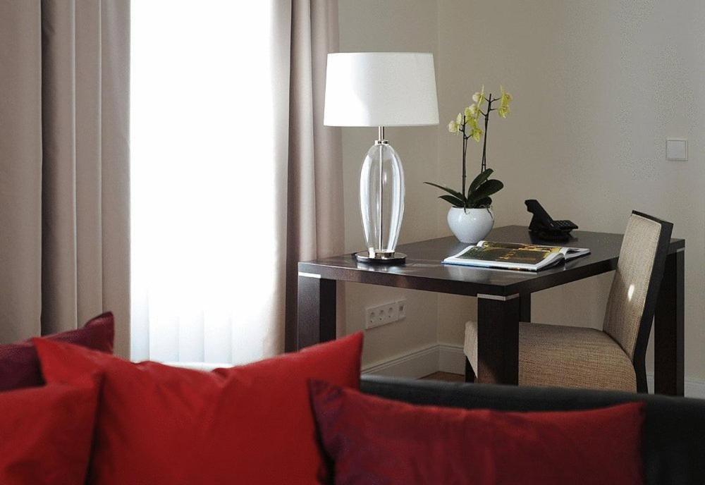 a table with a lamp and a table with red pillows at Villa Sternkopf Suiten Rittersgrün in Breitenbrunn