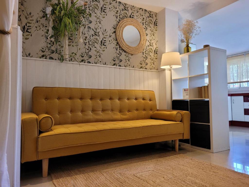 a yellow couch in a living room with a mirror at "COZY LOFT", TERRACE, PARKING and SWIMMING POOL in Málaga