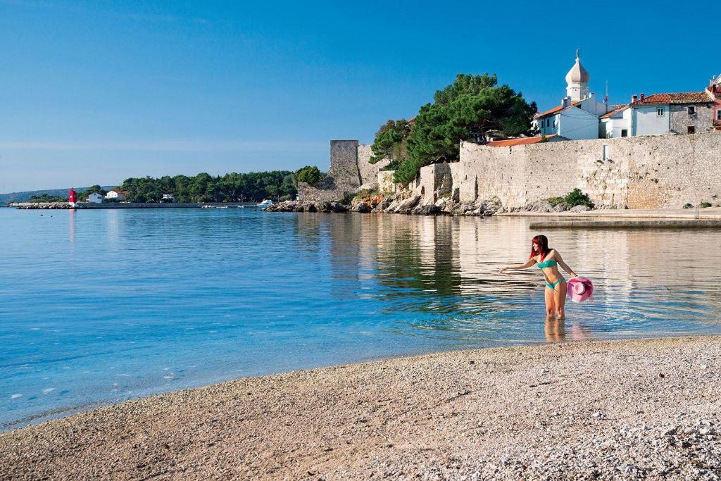 a girl standing in the water on a beach at Double Room Krk 5294b in Krk