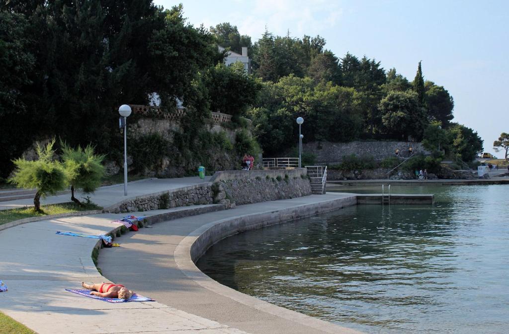 a group of people laying on the side of a body of water at Double Room Krk 5294b in Krk