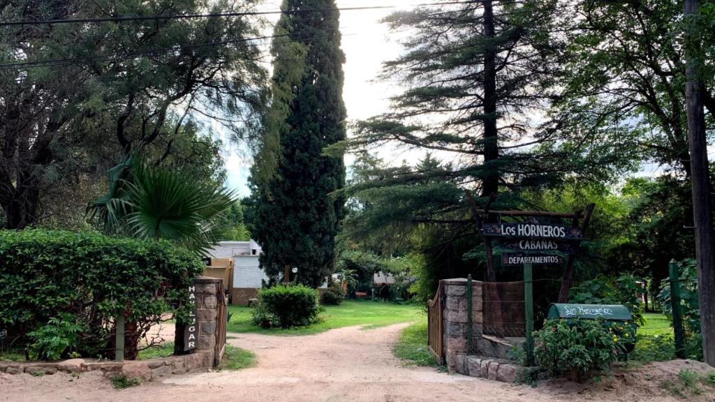 una puerta a una casa con un letrero de la calle y árboles en Los Horneros, Cabañas en San Marcos Sierras