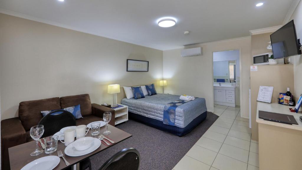 ein Hotelzimmer mit einem Bett und einem Wohnzimmer in der Unterkunft Chinchilla White Gums Motor Inn in Chinchilla