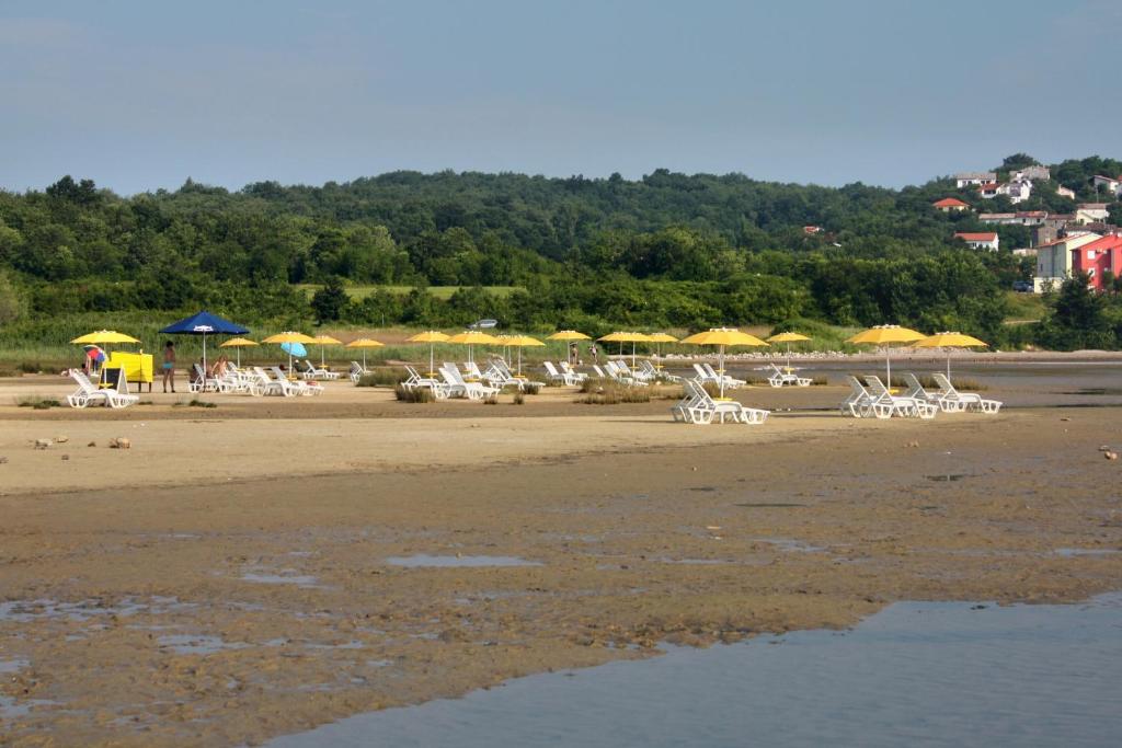 a group of chairs and umbrellas on a beach at Apartments with a parking space Zupanje, Krk - 5307 in Županje