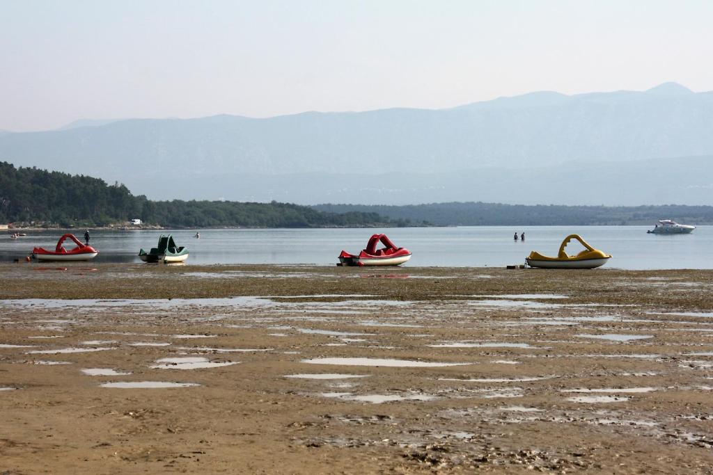 three boats sitting on the shore of a body of water at Apartments with a parking space Zupanje, Krk - 5307 in Županje