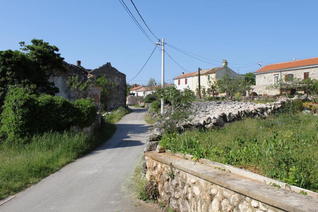 a road with a stone wall next to a street at Apartments with a parking space Zupanje, Krk - 5307 in Županje