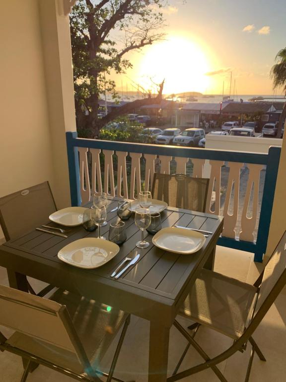 MarigotにあるDuplex Cosy au cœur de Marigotの木製テーブル(皿付)、バルコニー(ワイングラス付)