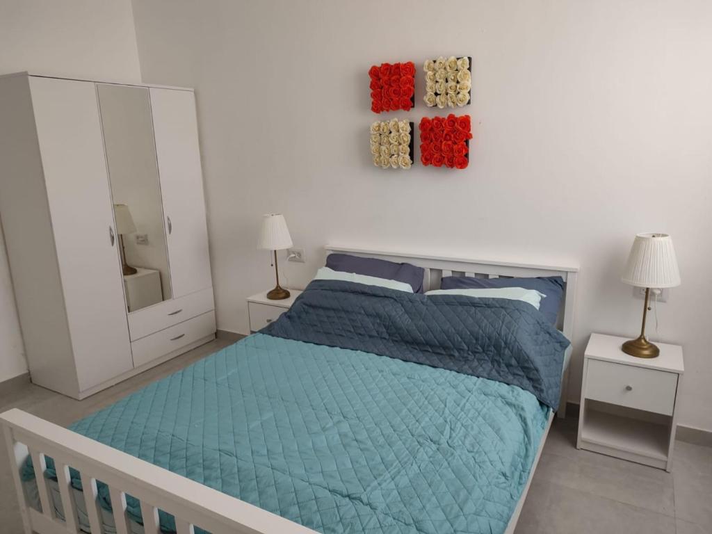 biała sypialnia z łóżkiem i lustrem w obiekcie Lovely three-room apartment above the promenade w mieście Aszdod