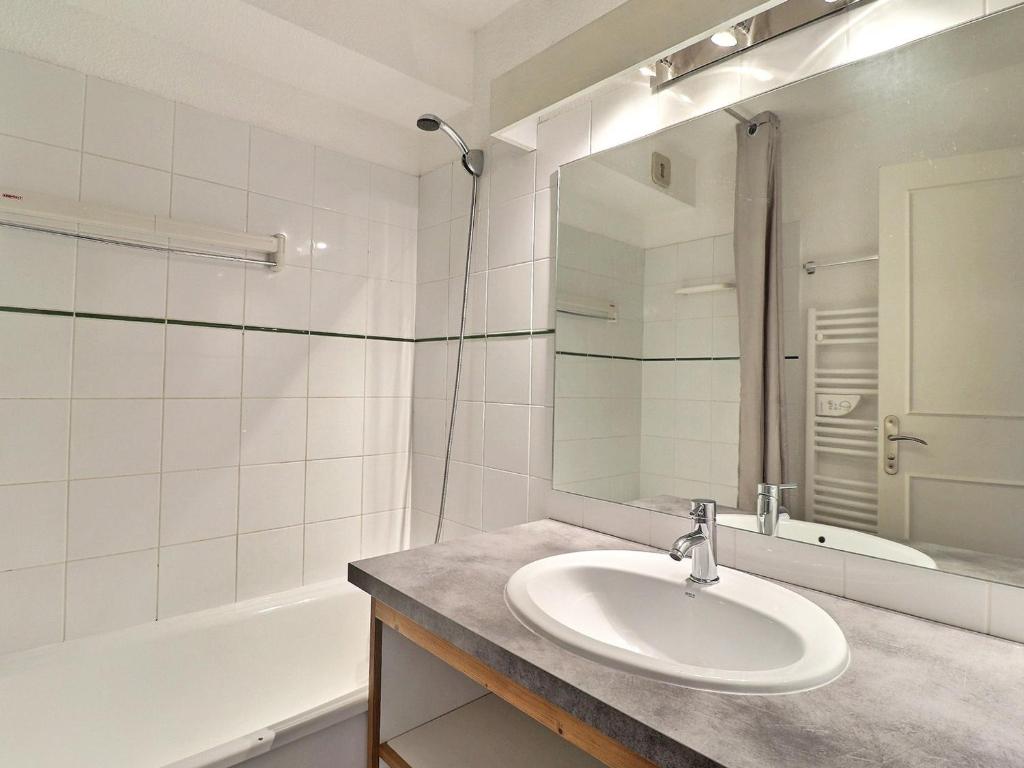W łazience znajduje się umywalka, wanna i lustro. w obiekcie Appartement La Tania 4 pers, skis aux pieds, 2 pièces, balcon, résidence Grand Bois A - FR-1-182A-19 w Courchevel