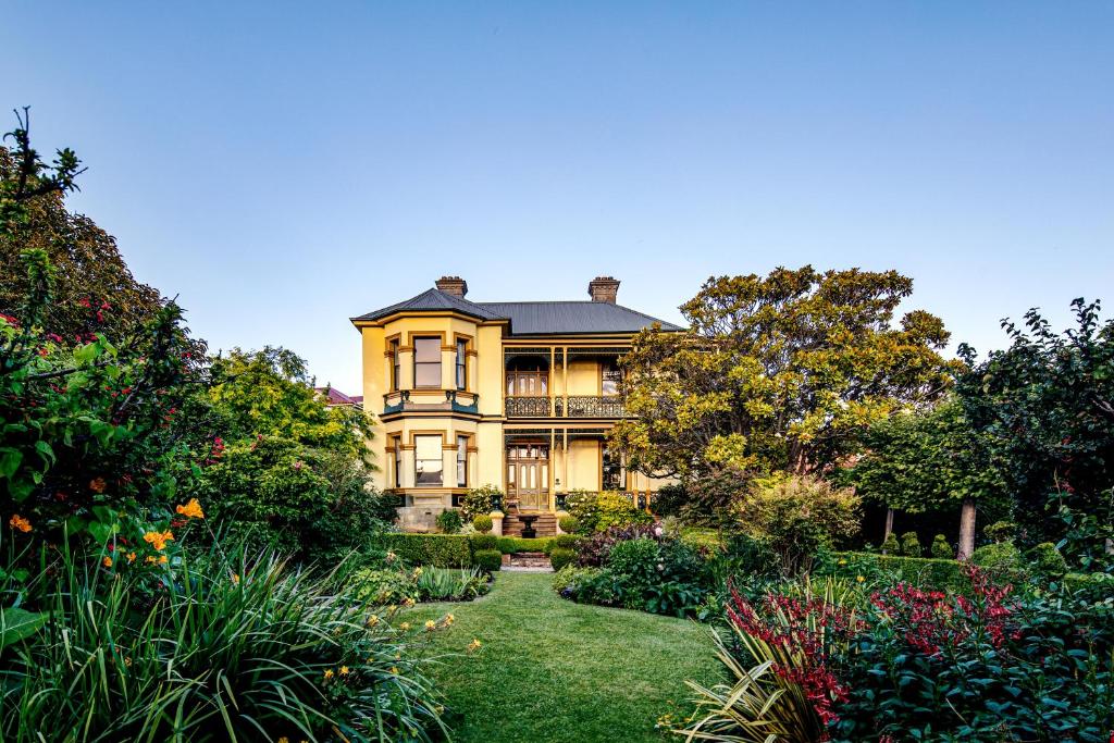 uma grande casa amarela com um jardim em frente em The Corinda Collection em Hobart