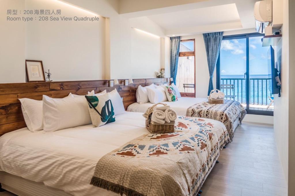 a bedroom with two beds and a balcony at Chuanfanrock Haku Beach Days Inn in Eluan