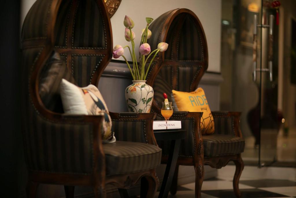 two chairs and a vase with flowers on a table at Hanoi Garden Hotel & Spa in Hanoi