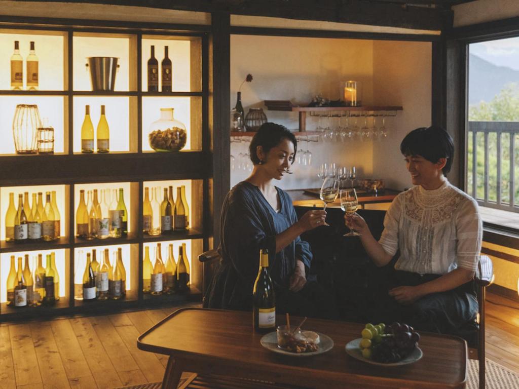 山梨的住宿－古民家宿るうふ 丘之家 Okanoie，两个女人坐在桌子边,喝杯酒