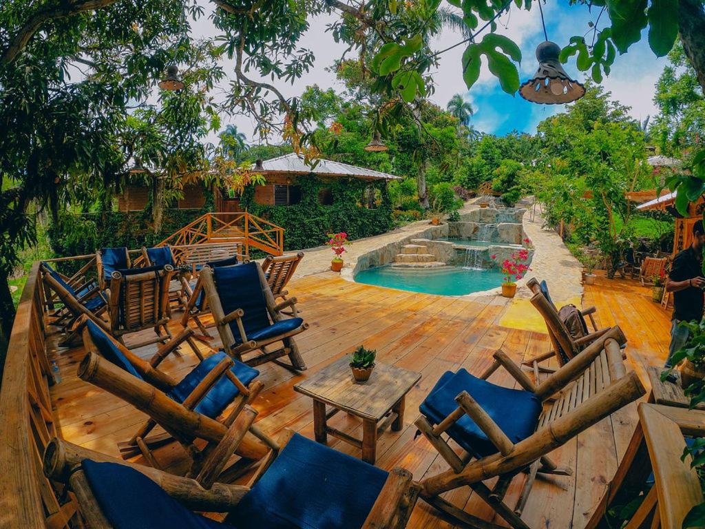 a group of chairs sitting on a deck next to a pool at EL GALLO ECOLODGE in San Felipe de Puerto Plata